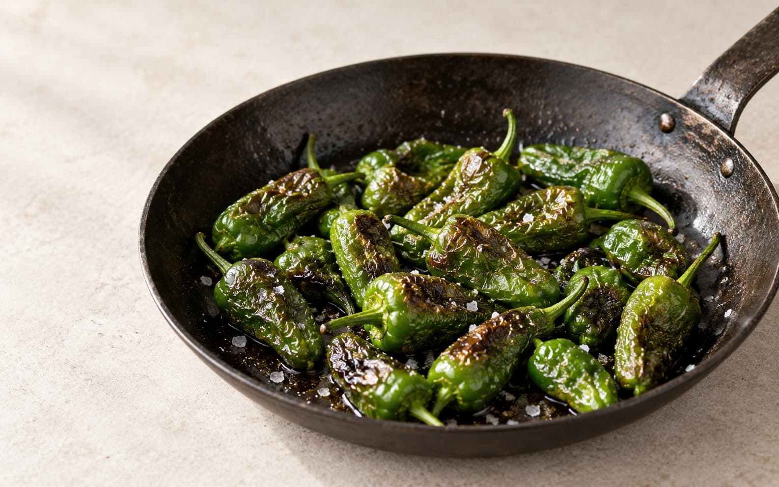 Pimientos de Padrón recién hechos en una sartén de hierro, con sal gruesa y un poco de aceite
