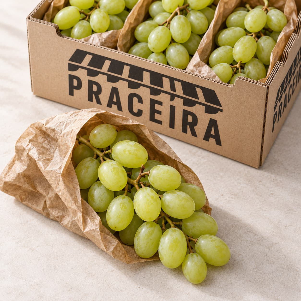 Racimo de uva blanca que asoma de una bolsa de papel, con la caja detrás